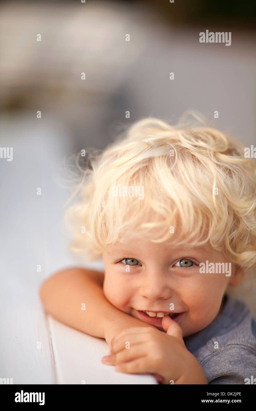Close Up Portrait Of Smiling Blonde Toddle Boy With Curly Hair