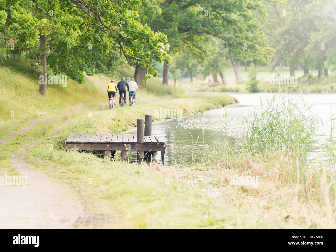 Tranquil summer landscape. People biking on trail by Gota Canal in Sweden. Stock Photo