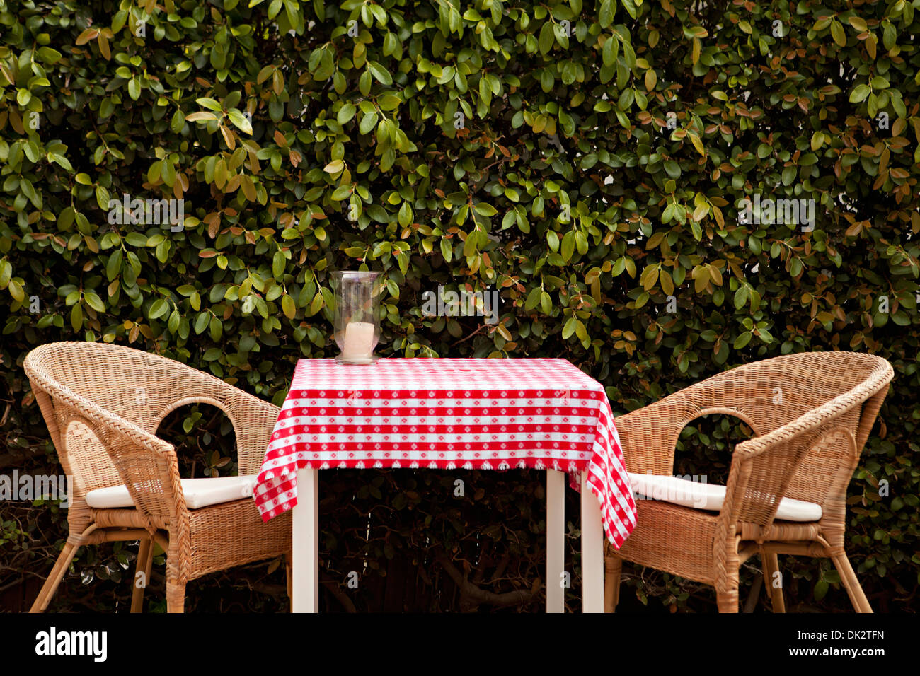 Wicker chairs at patio table with red and white tablecloth Stock Photo
