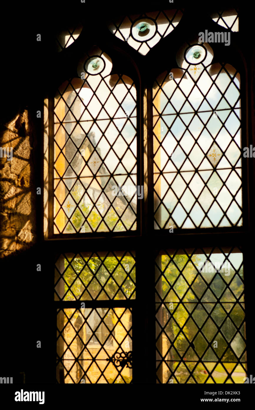 Silhouetted Gothic leaded glass window overlooking sunny garden Stock Photo