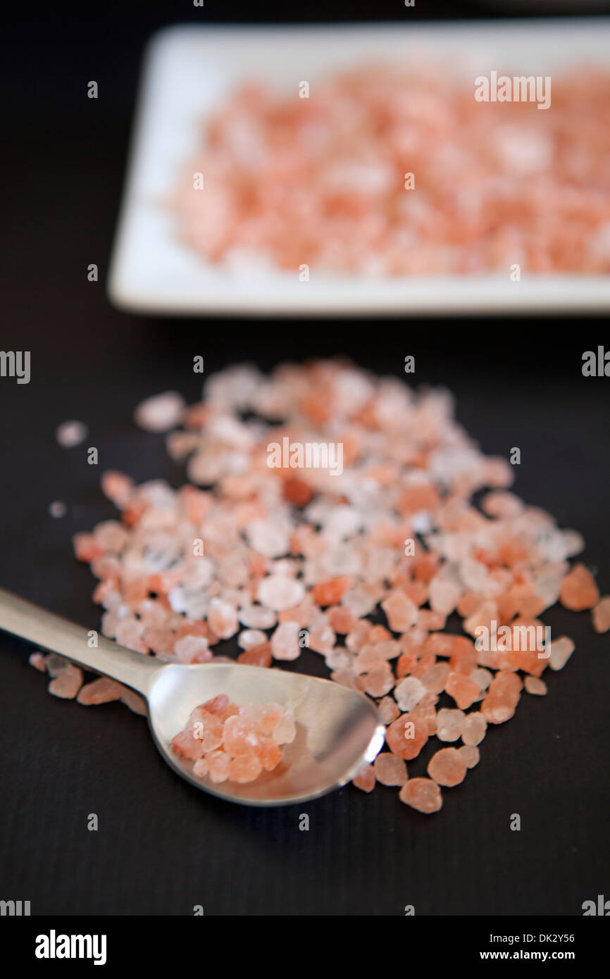 Close up of pink cooking rock salt in spoon and on platter Stock Photo