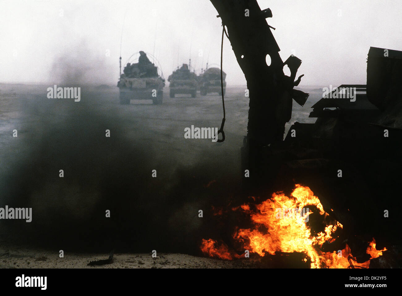 Armored personnel carriers of the 7th Brigade Royal Scots, 1st United Kingdom Armored Division, pass a burning Iraqi anti-tank vehicle while advancing east into Kuwait from southern Iraq during Operation Desert Storm February 28, 1991 in Kuwait. Stock Photo