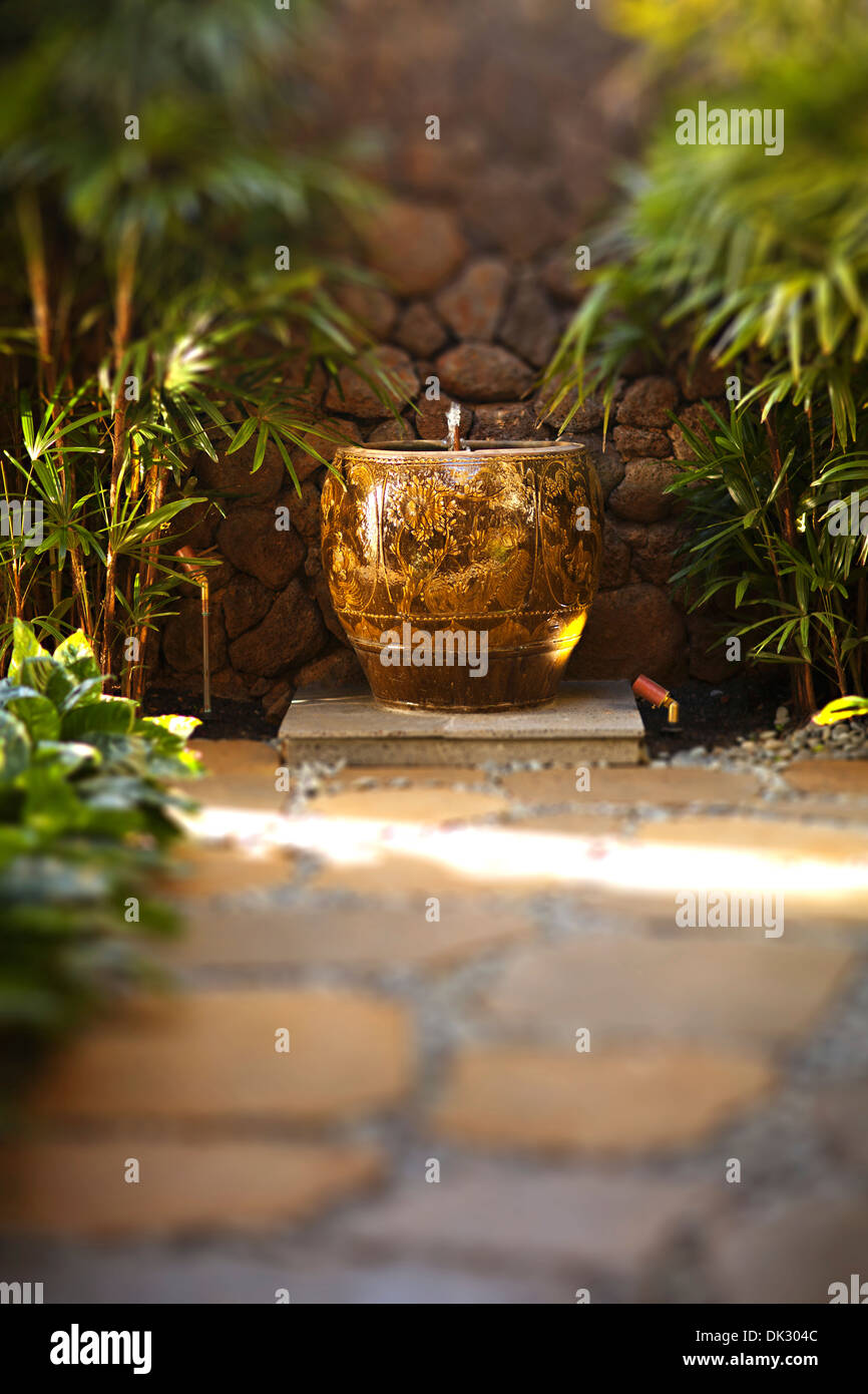 Stone path and water fountain in tranquil tropical garden Stock Photo