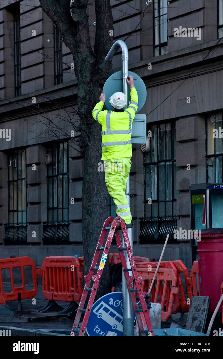 City Council worker standing up on a ladder repairing a traffic road sign along a side street in Dundee, UK Stock Photo