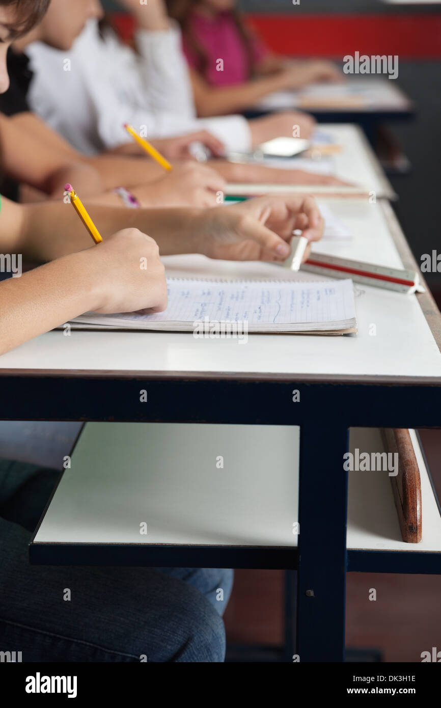Schoolchildren Writing In A Row At Desk In Classroom Stock Photo Alamy