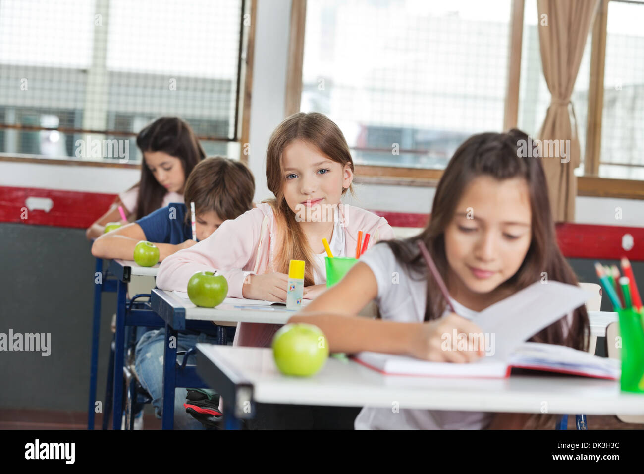 Schoolgirl Sitting At Desk With Classmates In A Row Stock Photo - Alamy