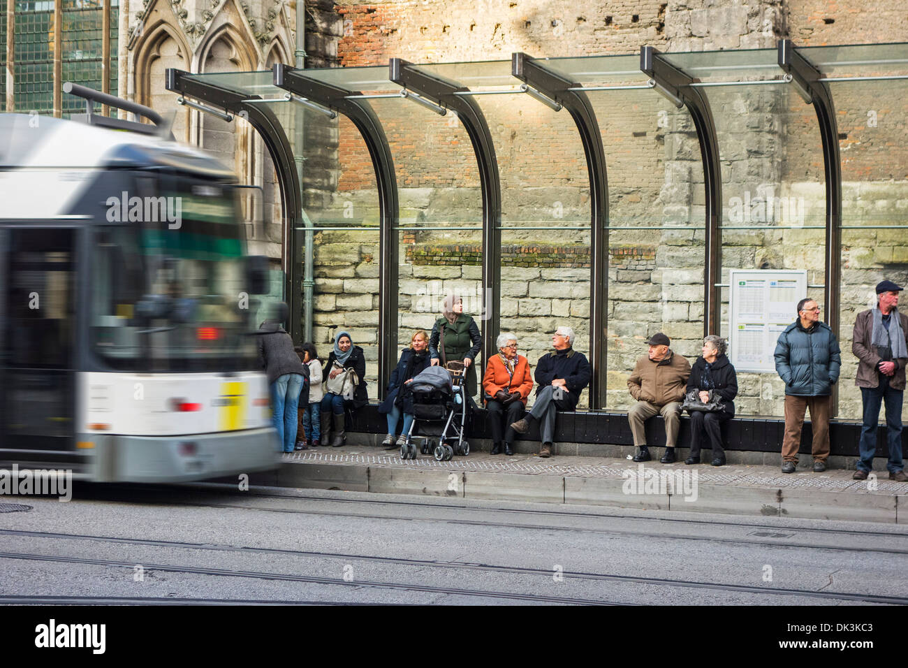 Elderly people and migrant mother with pram waiting for tram at tramstop platform in city Stock Photo