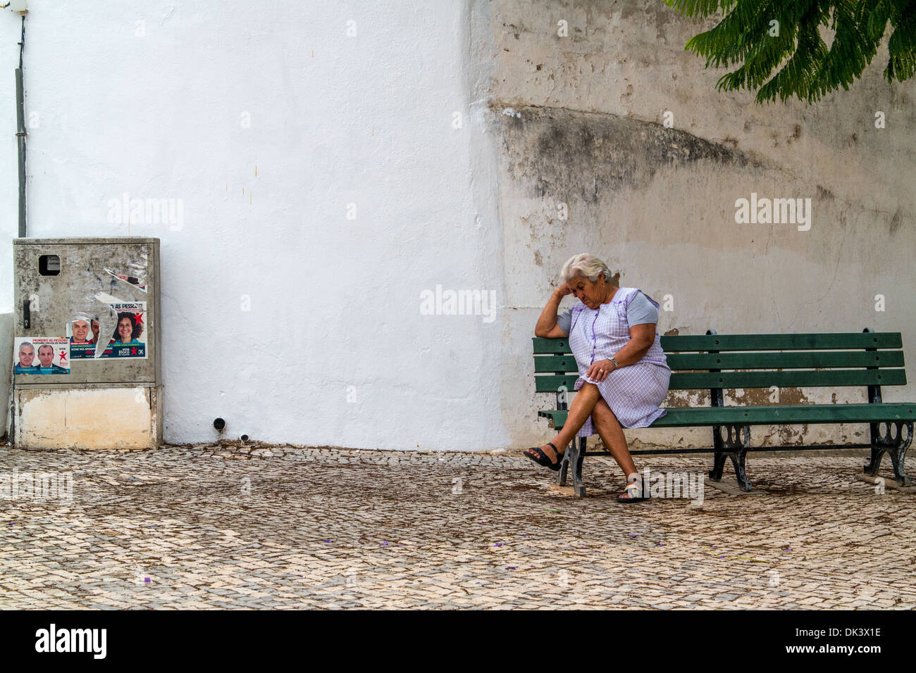 Elderly lady having 5 minutes rest during the day sat on a green bench Stock Photo