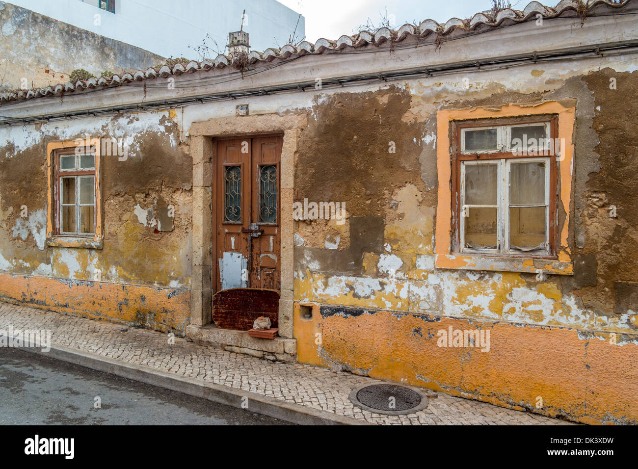 Old building in a state of dilapidation with paint and cement peeling off the walls Stock Photo