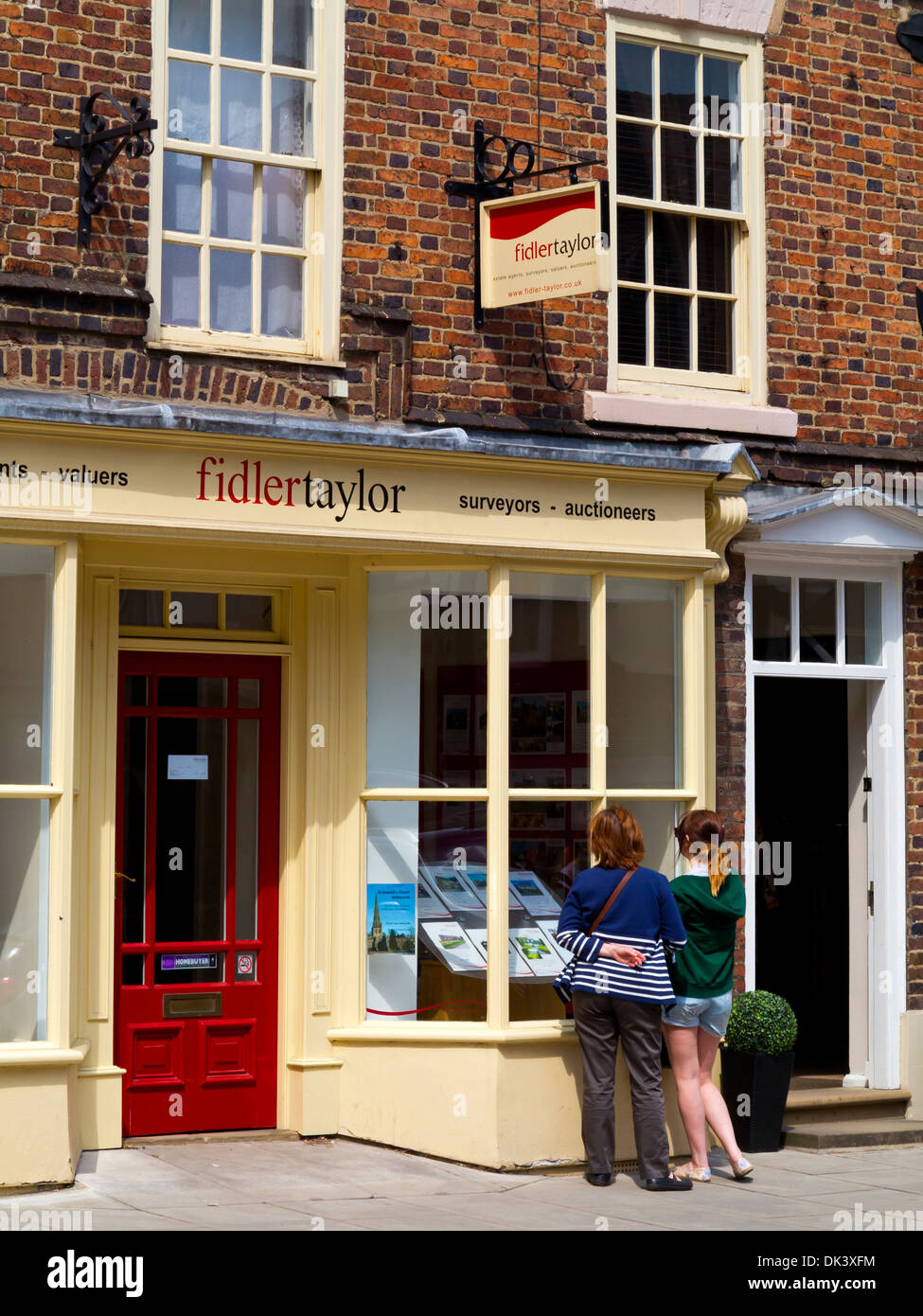 Two women looking at houses for sale in a branch of Fidler Taylor estate agents in Ashbourne Peak District Derbyshire England UK Stock Photo