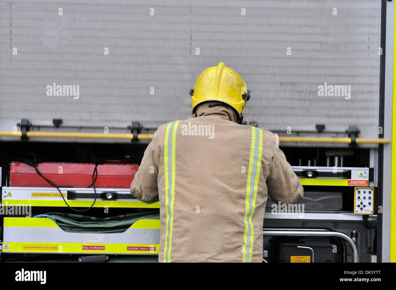 Firefighter closing the side compartment on a Scottish Fire and Rescue Service fire engine. Stock Photo