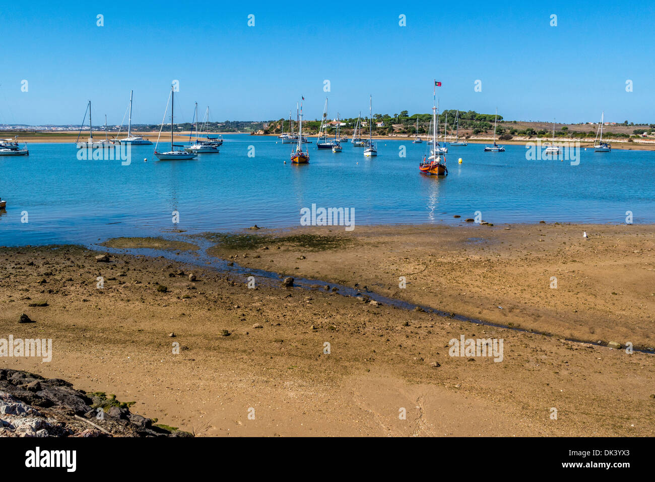Sandy beach looking out at the harbour with a Blue Sky and small boats Stock Photo