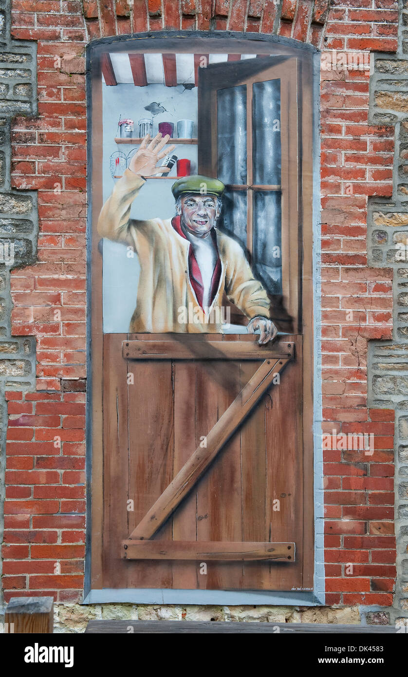hand painted mural of man waving from doorway, clecy, swiss normandy, france Stock Photo
