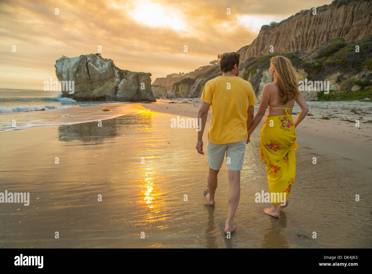 Couple holding hands walking along the beach Stock Photo - Alamy