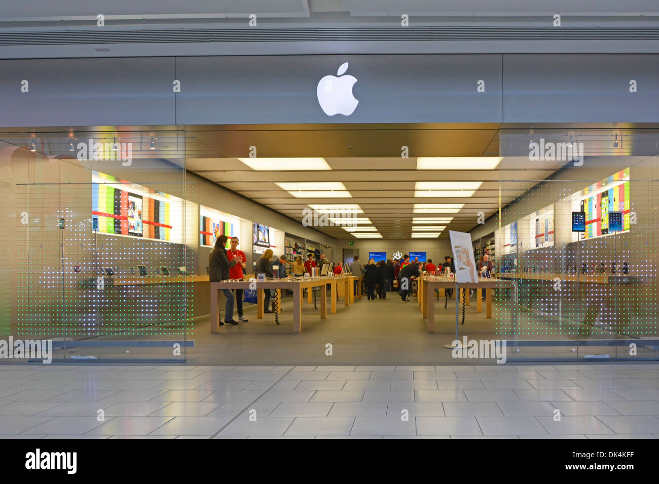 Apple logo above digital retail business computer technology store with people customers entry direct from indoor shopping mall West Thurrock Essex UK Stock Photo