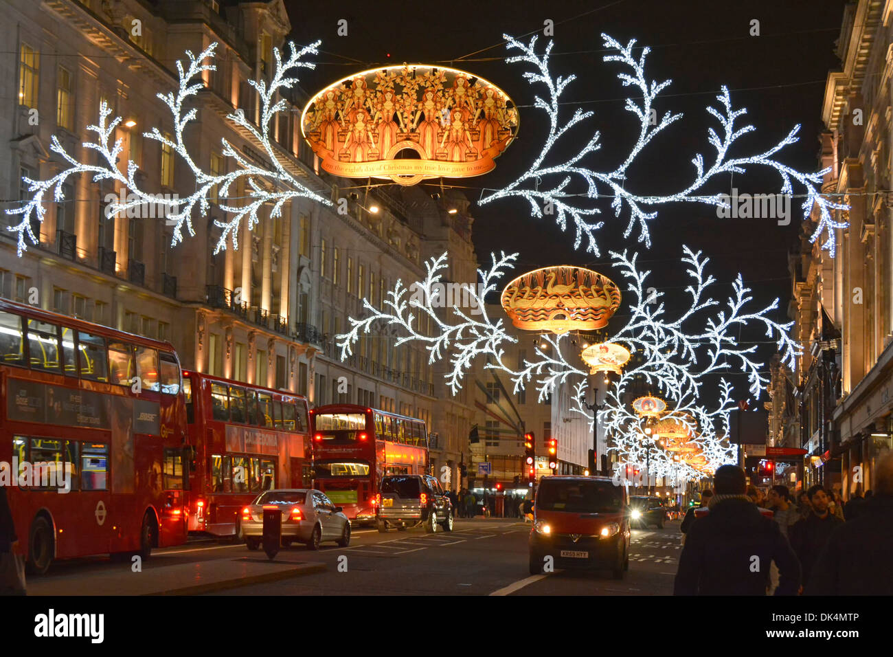 Night evening winter street scene and road traffic in Regent Street annual Christmas illuminations and decorations West End London England UK Stock Photo