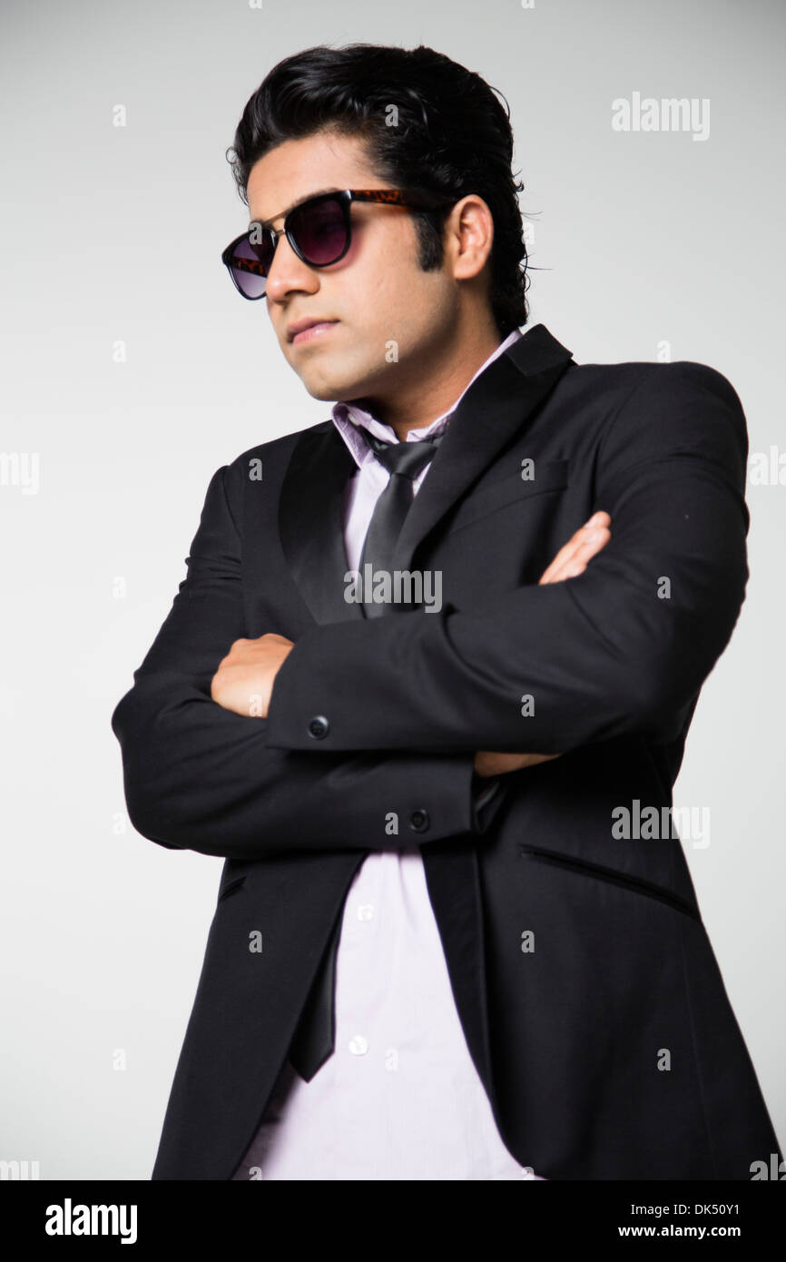 Young Indian man in jacket, tie and sunglasses with arms crossed Stock Photo
