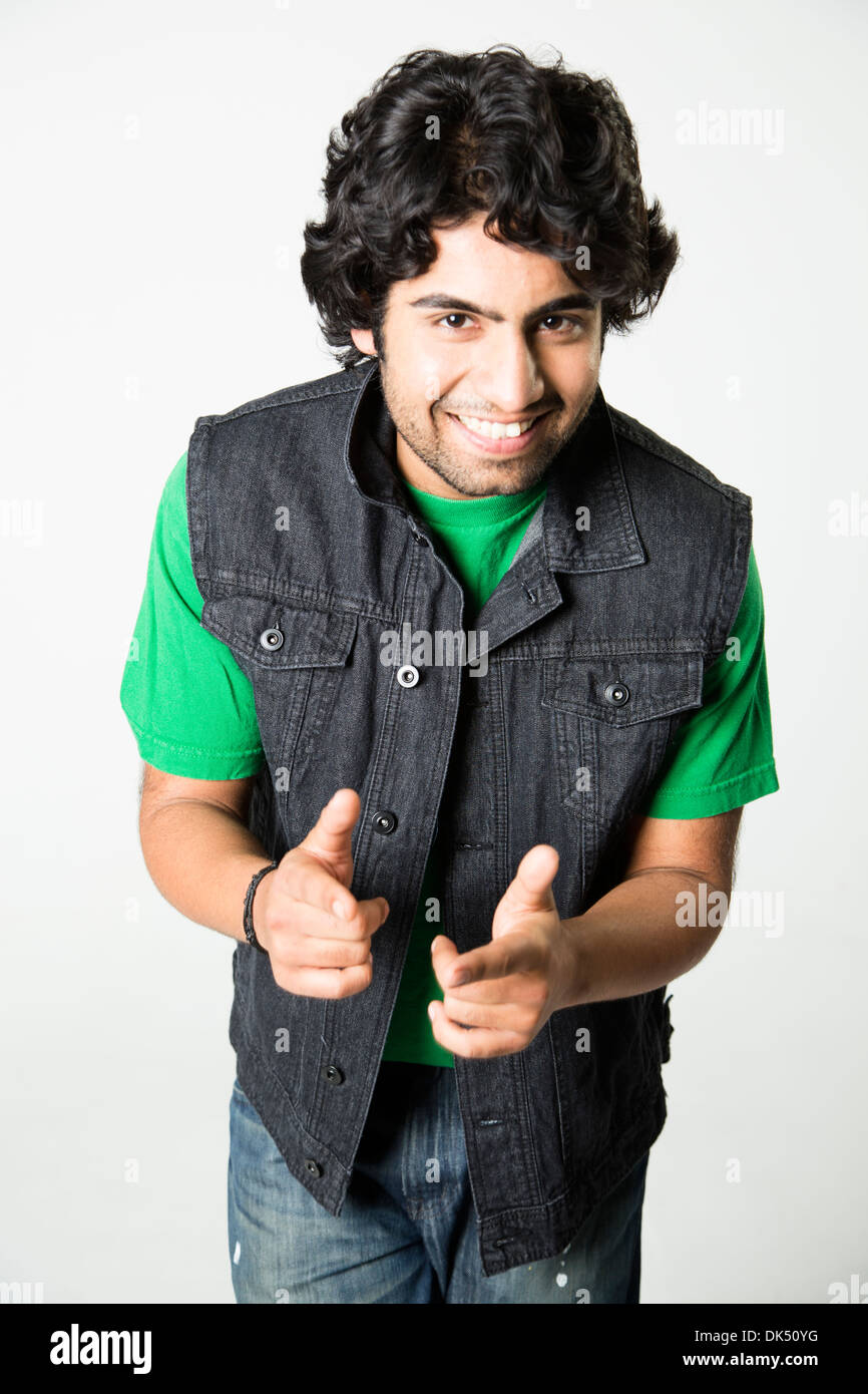 Smiling young Indian man dressed in denim pointing at camera Stock Photo