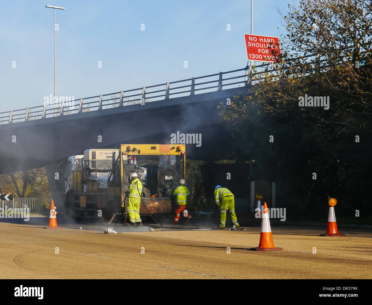 workmen carrying out repairs and resurfacing work on a busy main road. Stock Photo