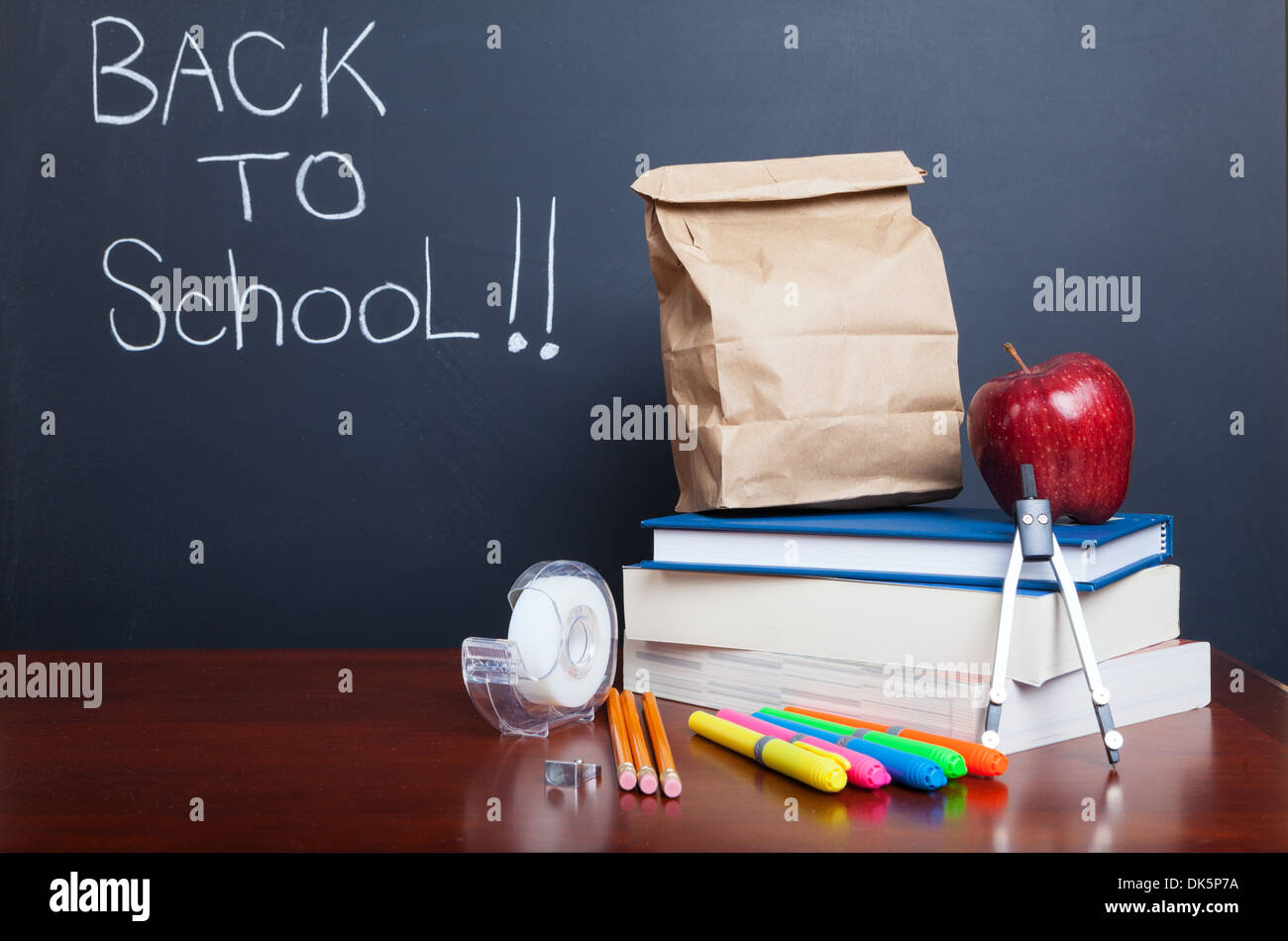Back to school, school books with apple and paper bag lunch on desk Stock Photo