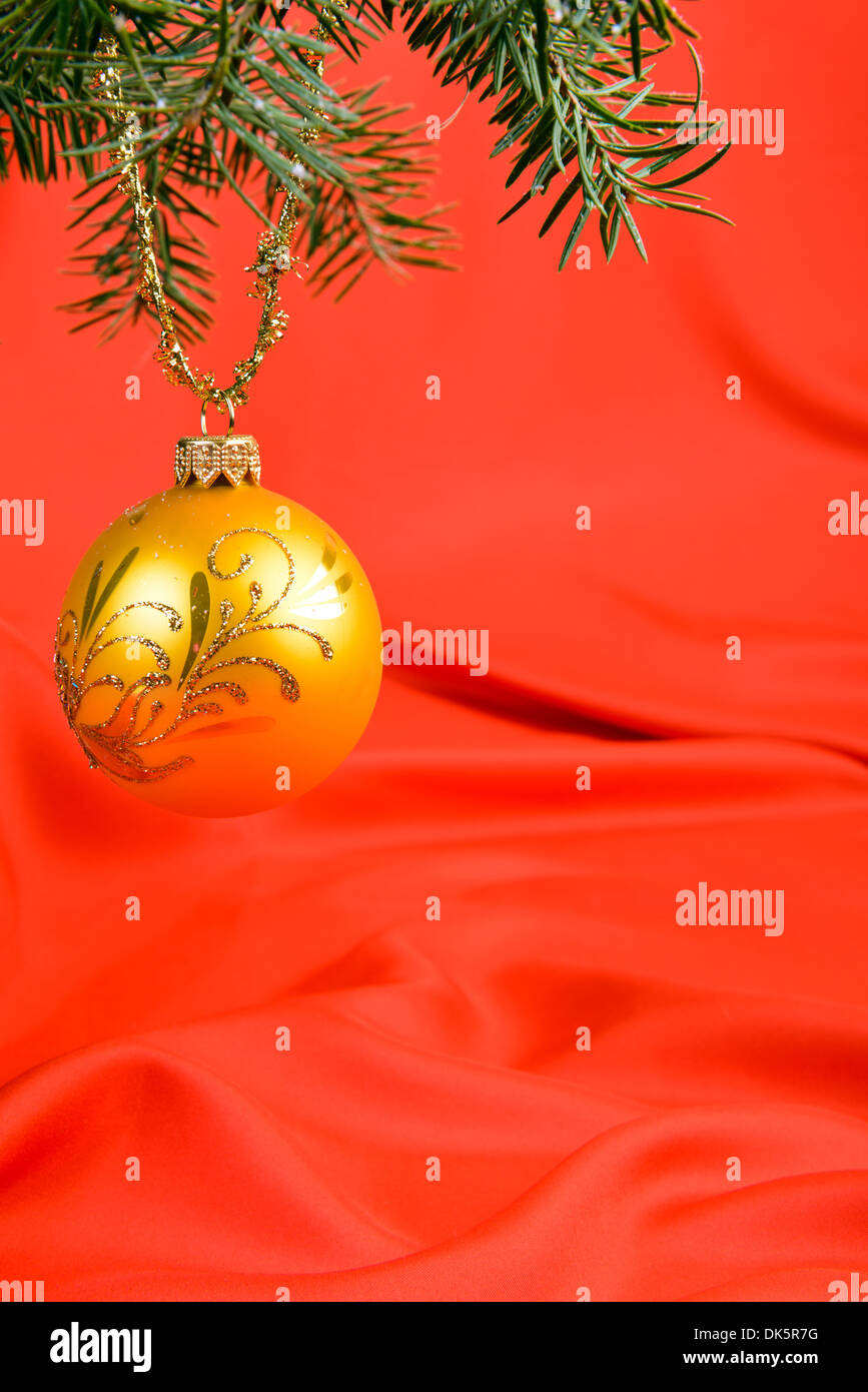 Christmas tree branch and ball on a red silk background Stock Photo