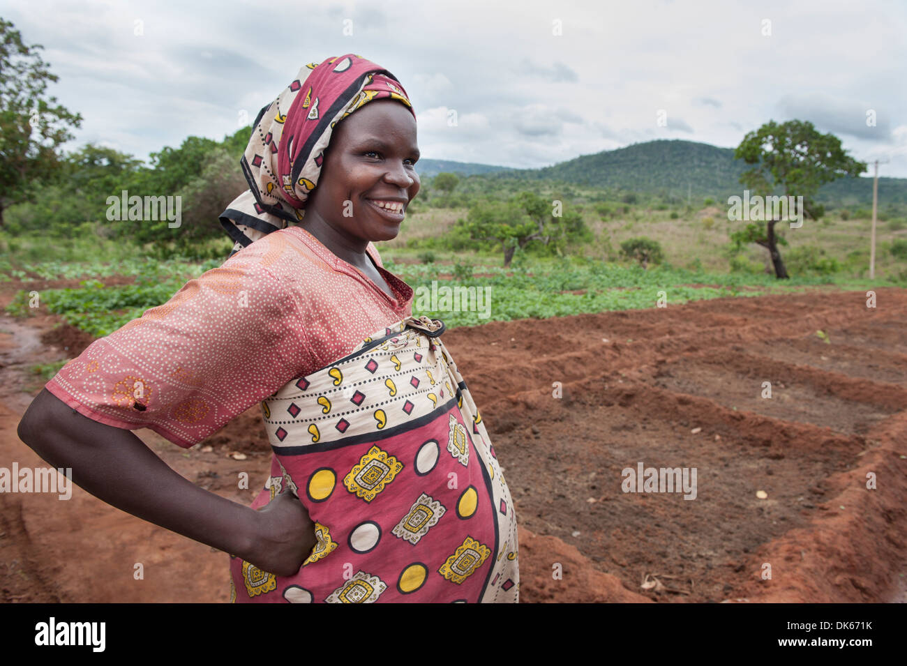 A pregnant woman takes a rest from tilling her land Stock Photo