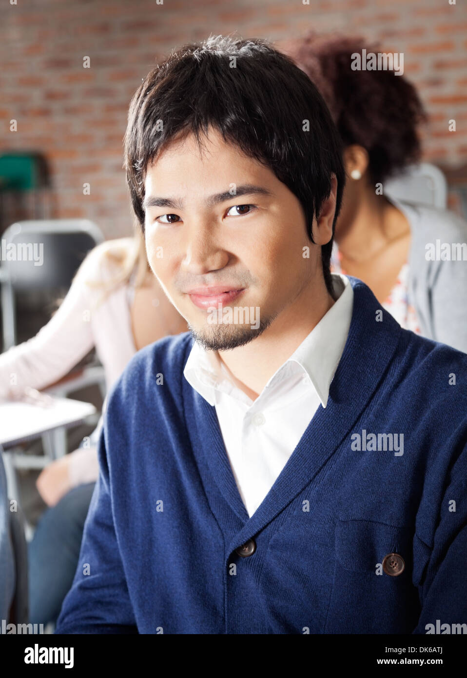 Student sitting with classmates in background at classroom stock photo