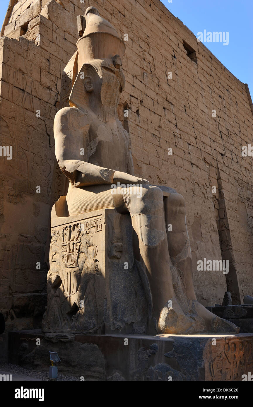 Seated statue of Ramesses II and First Pylon at entrance to Luxor Temple - Luxor, Egypt Stock Photo