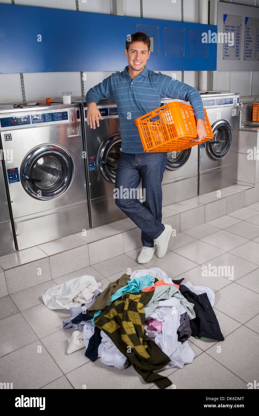 Happy Man Holding Empty Basket With Dirty Clothes On Floor Stock Photo