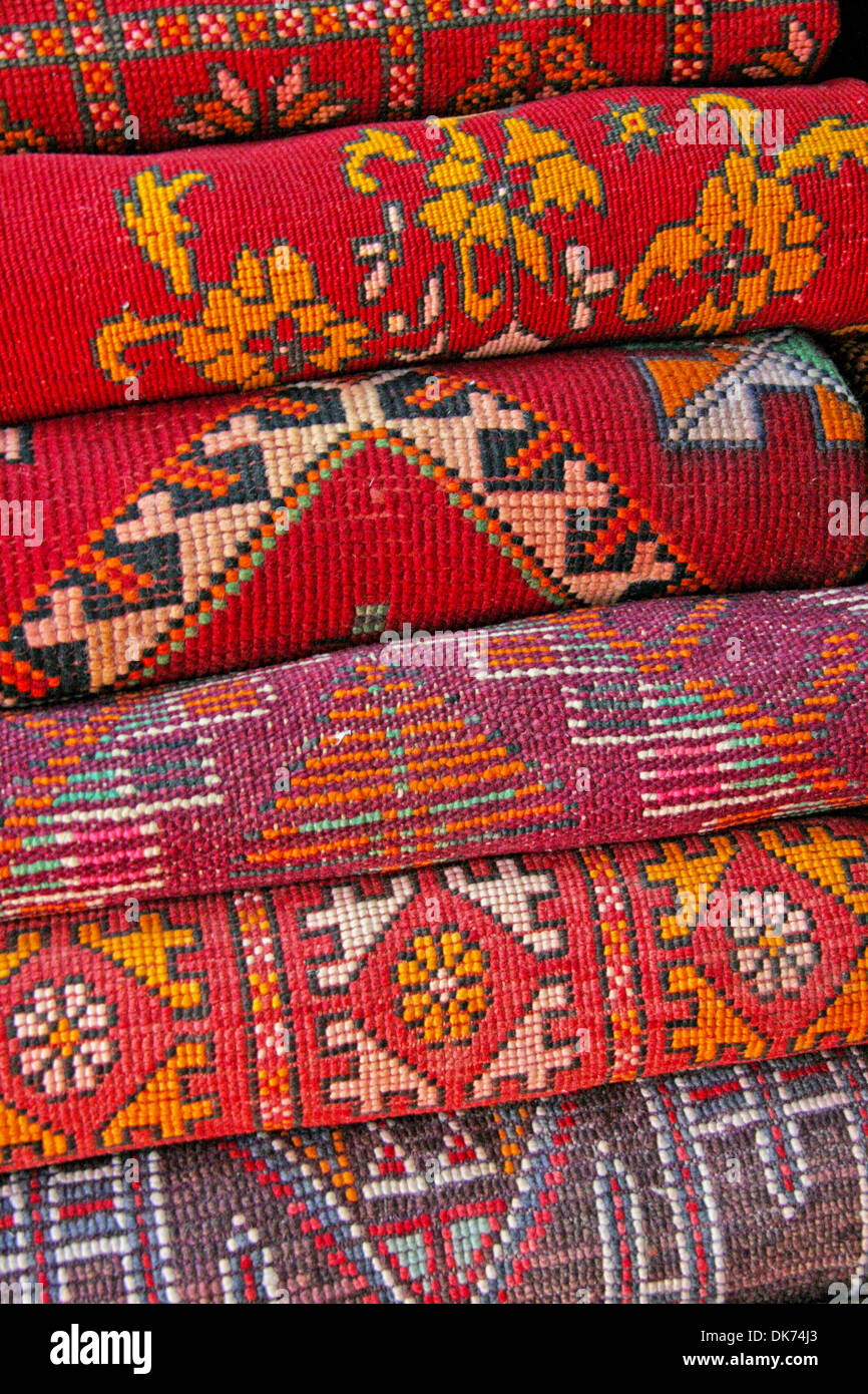 Pile of north african rugs in red, orange & brown shades, Morocco. Stock Photo