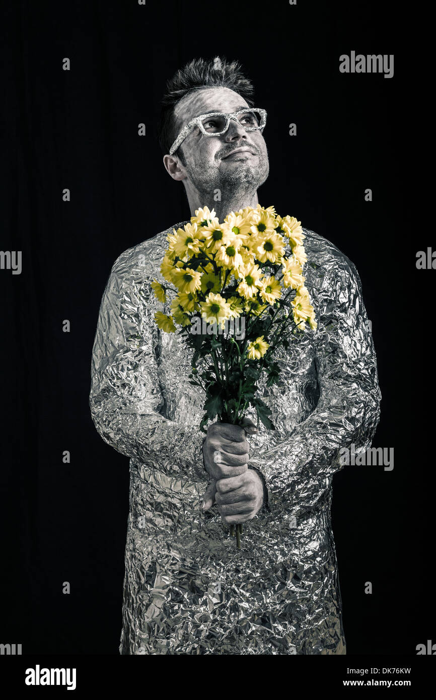 Portrait of happy spaceman holding flowers and looking up. Stock Photo