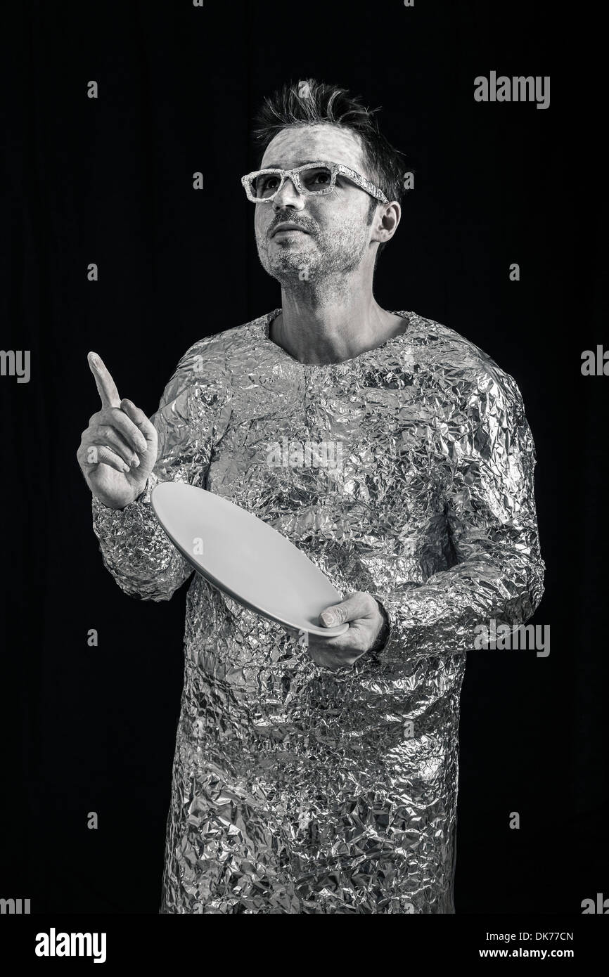 Portrait of spaceman holding UFO flying saucer and pointing up. Stock Photo