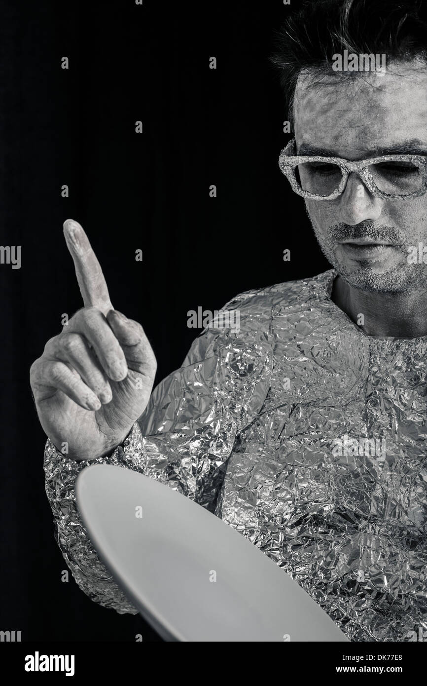 Portrait of spaceman holding UFO flying saucer and pointing up. Stock Photo
