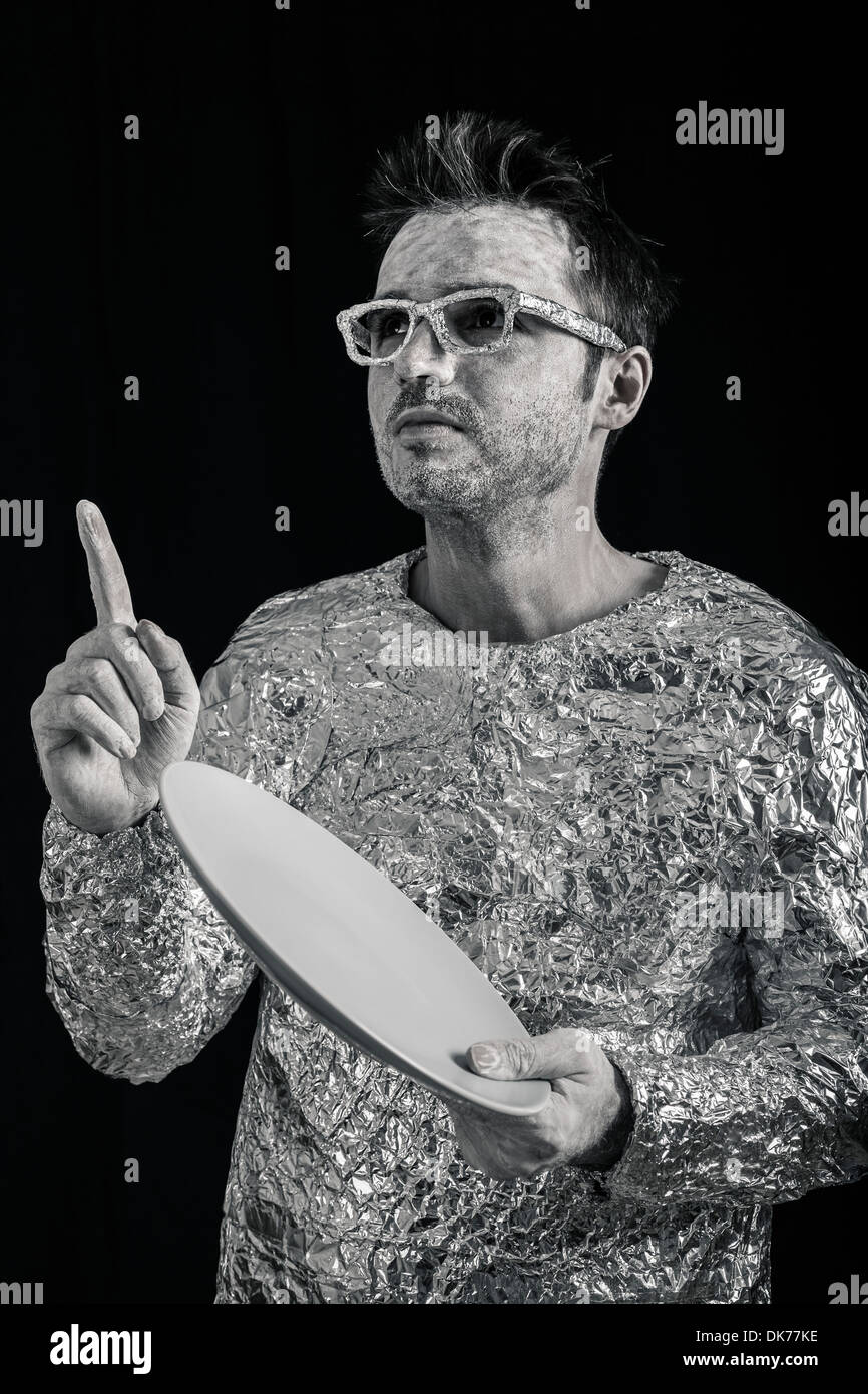 Portrait of spaceman holding UFO flying saucer and pointing up. Stock Photo