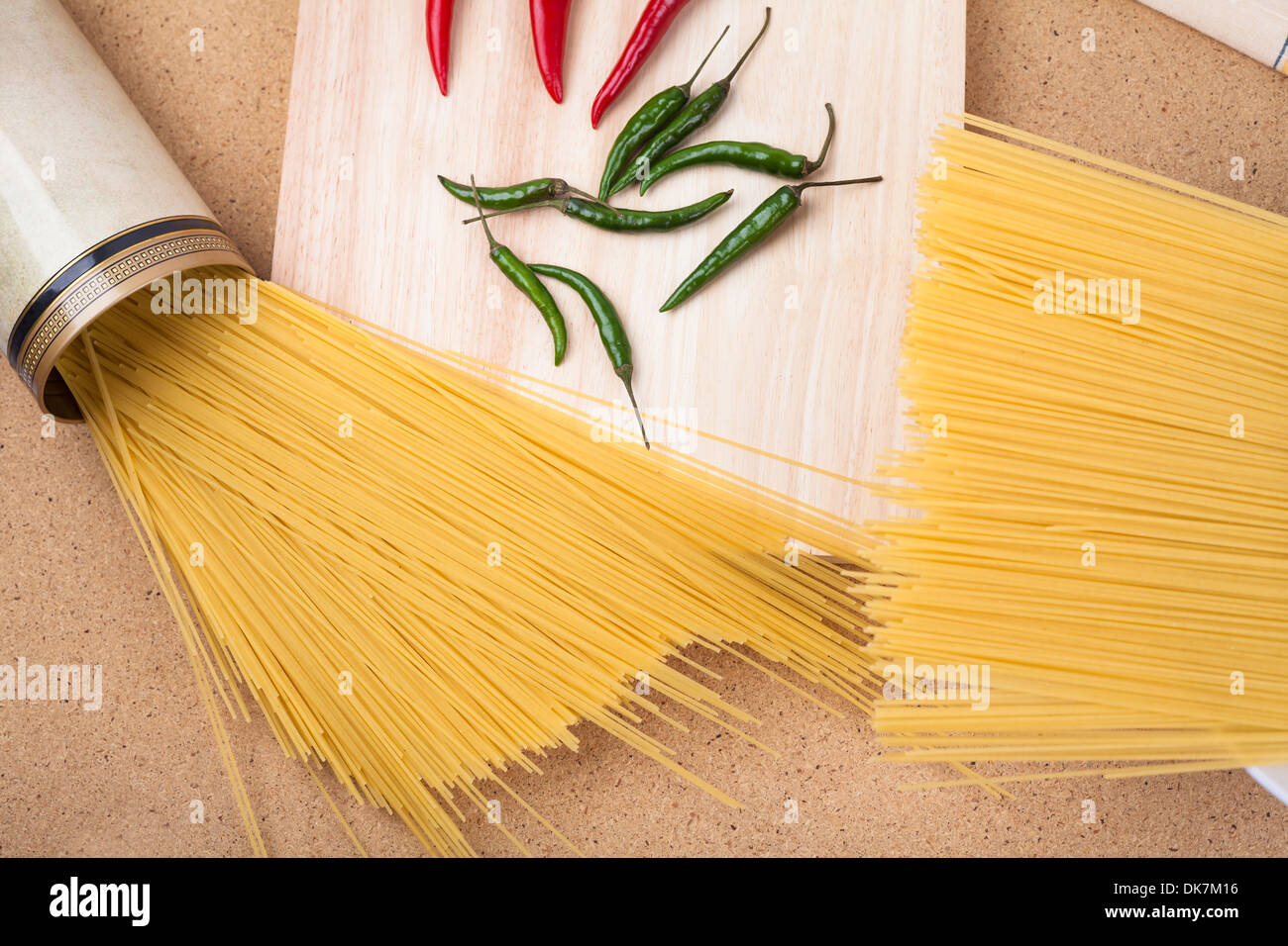 Dried uncooked pasta and chili peppers on wooden table. Stock Photo