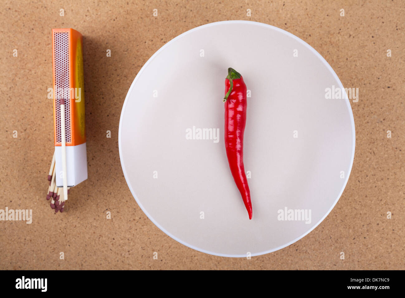 Plate with fresh red hot chili peppers and matches on the table. Stock Photo