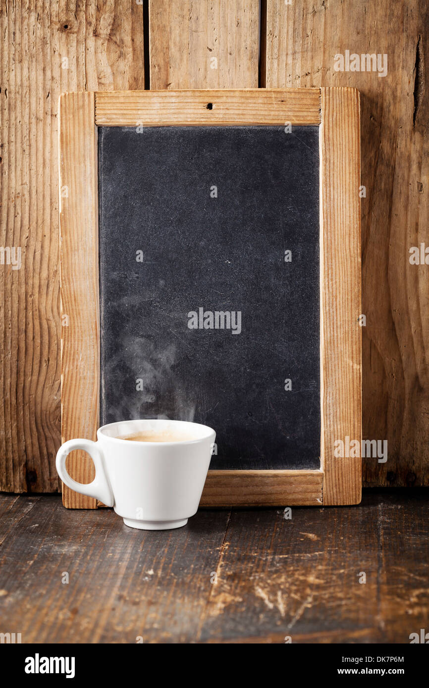 Coffee cup and Vintage slate chalk board on wooden background Stock Photo