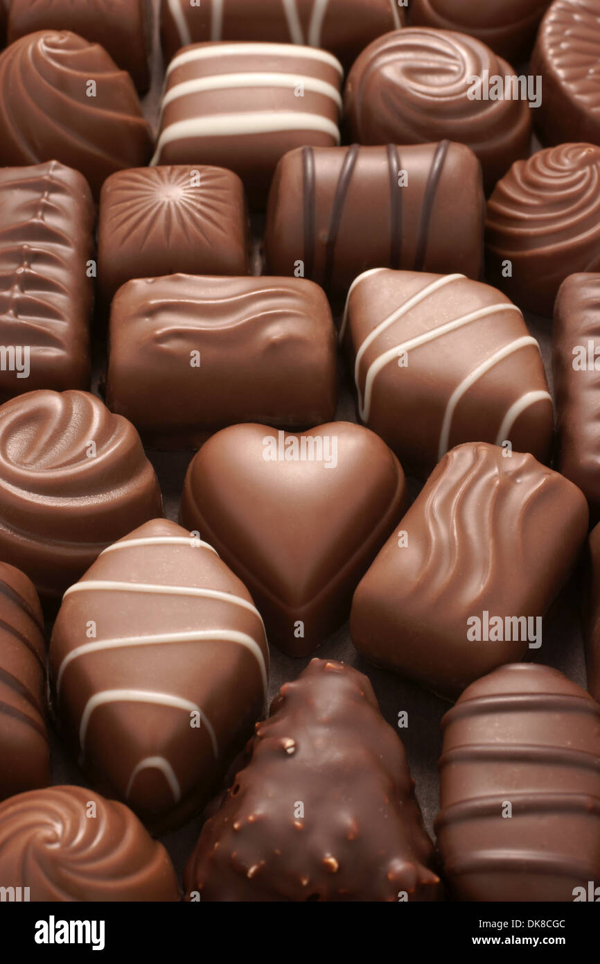 A chocolate heart surrounded by assorted milk chocolates in a box Stock Photo