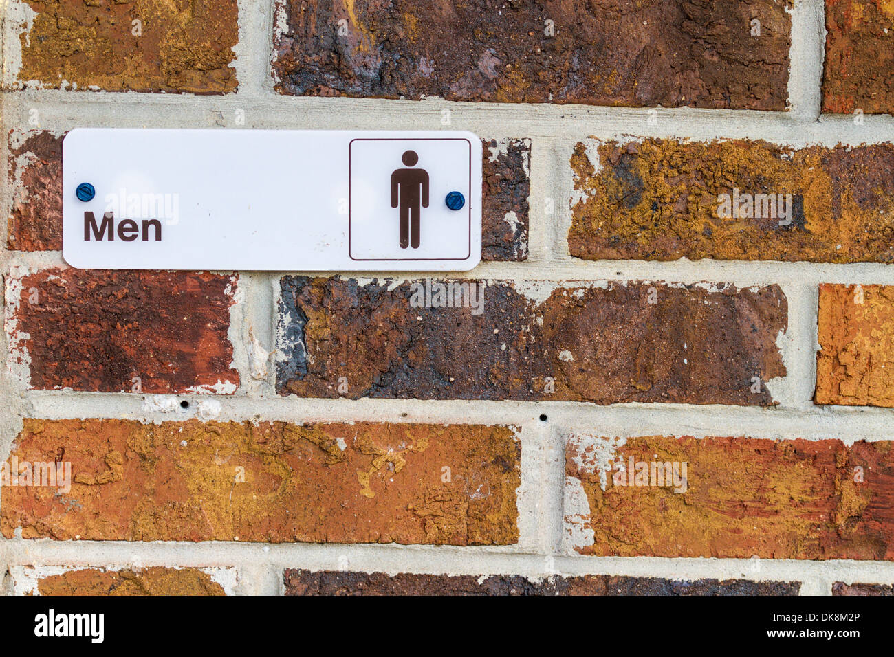 Sign on brick wall at entrance to Men's restroom. Stock Photo