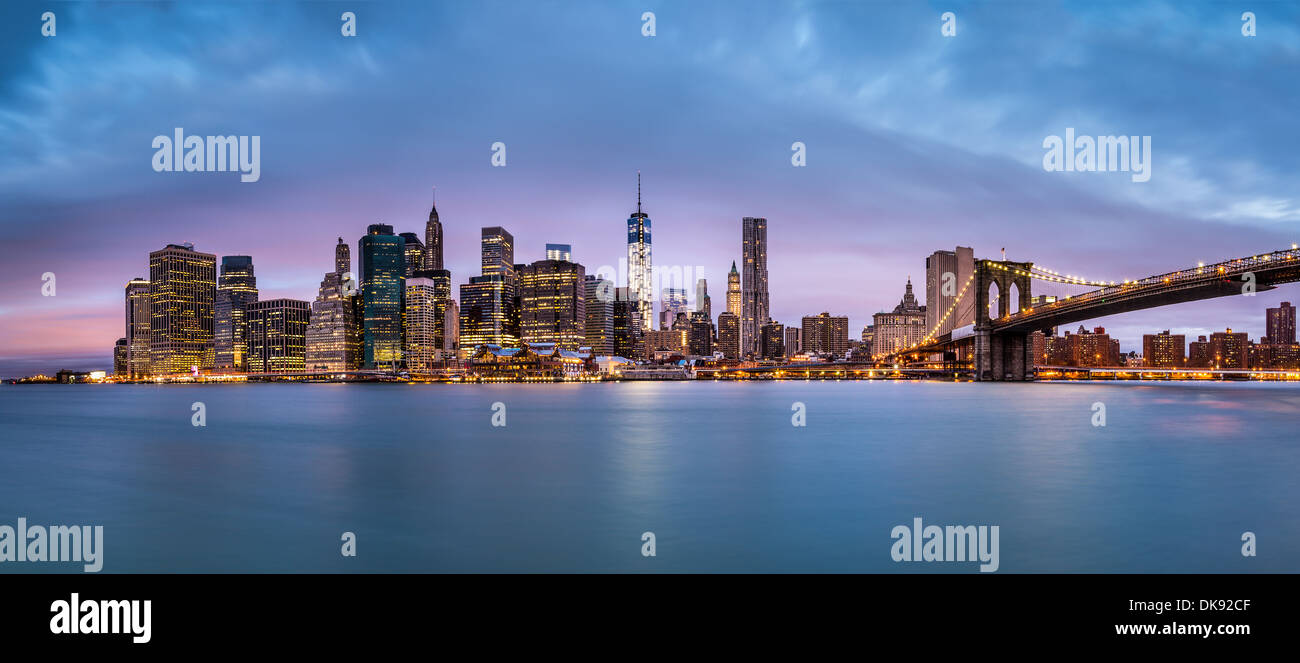 Lower Manhattan and the Brooklyn Bridge under a cloudy sky at dawn as viewed from the Brooklyn Bridge Park. Stock Photo