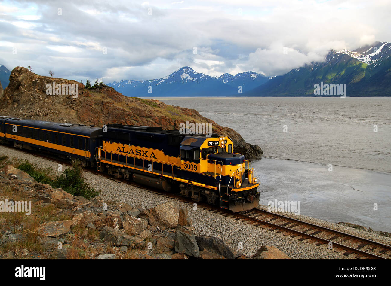Train on the Turnagain Arm in Alaska heading towards Anchorage with clouds. Stock Photo