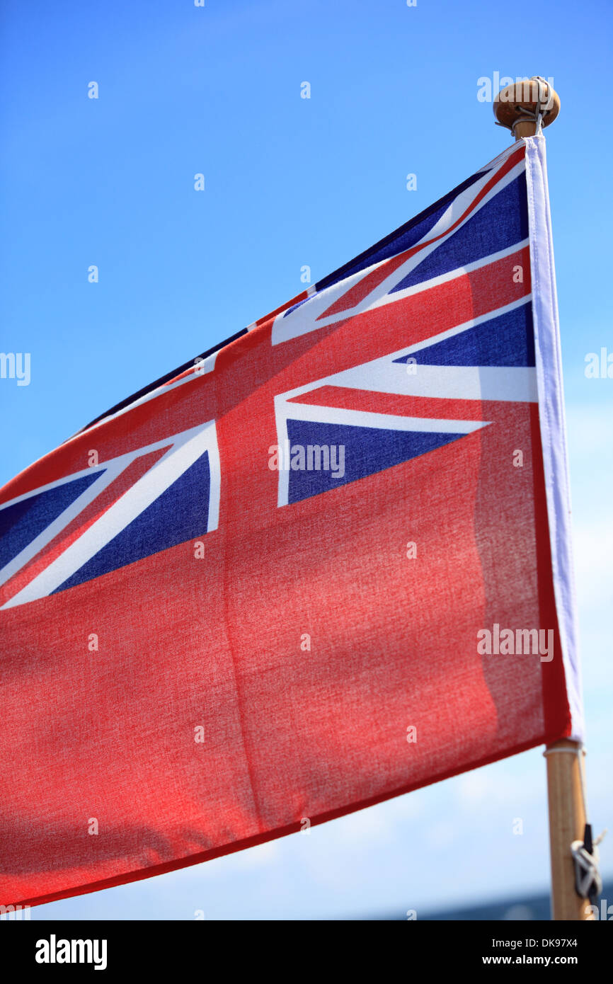 The UK red ensign the british maritime flag flown from a yacht sail boat blue sky Stock Photo