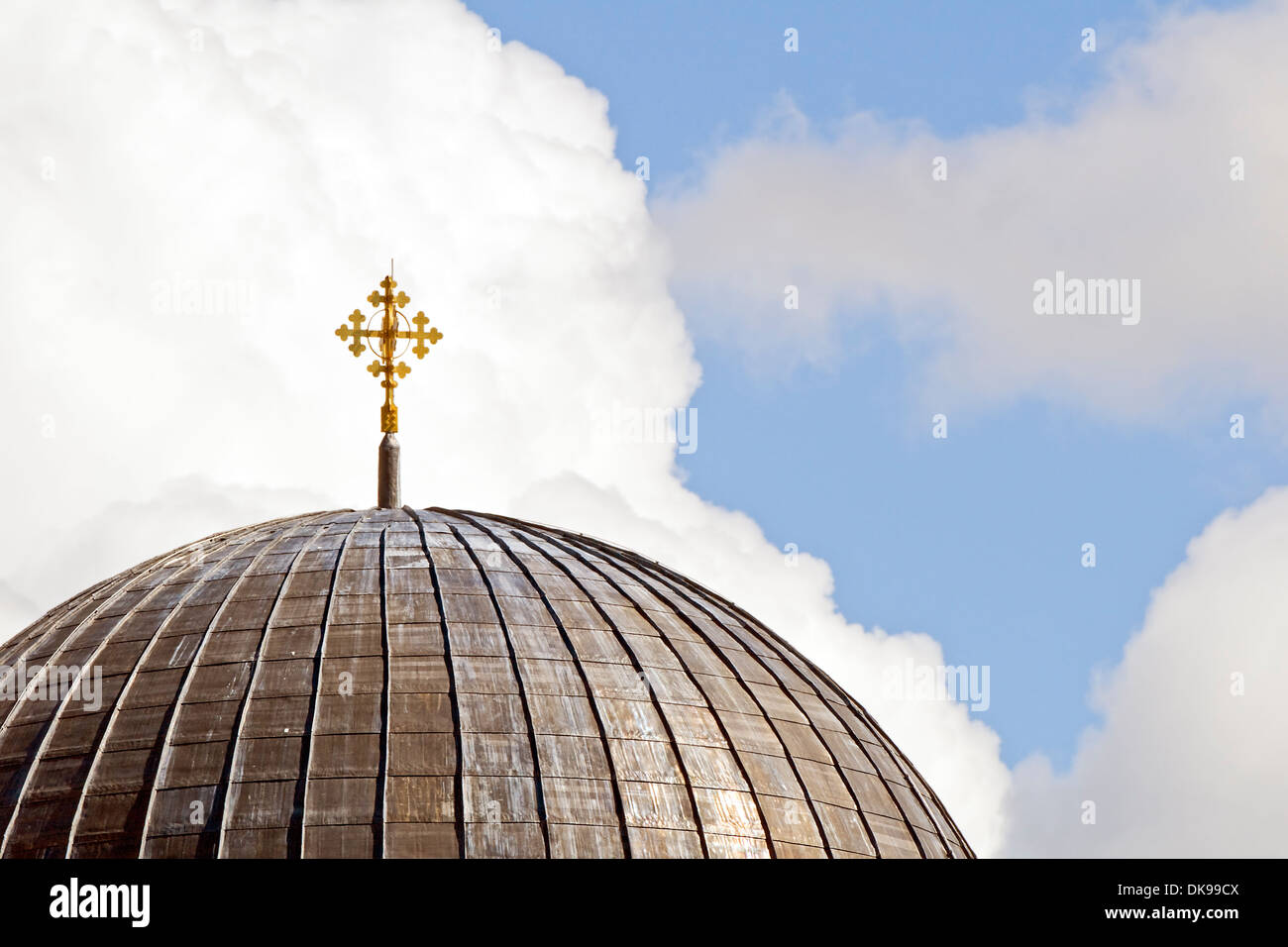 Close-up of a church dome with cross against a cloudy sky Stock Photo