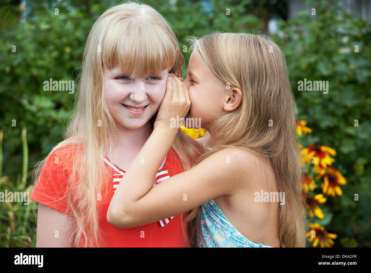 Girls tell each other secrets outdoors Stock Photo