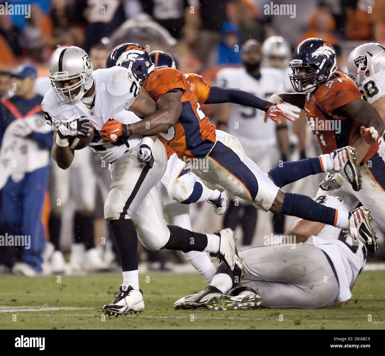 Sep. 12, 2011 - Denver, Colorado, U.S. - Raiders RB MICHAEL BUSH gets tackled from behind by Broncos S. BRIAN DAWKINS, right, during the 2nd half Monday night at Sports Authority Field at Mile High. The Oakland Raiders defeated the Denver Broncos 23-20. (Credit Image: © Hector Acevedo/ZUMAPRESS.com) Stock Photo