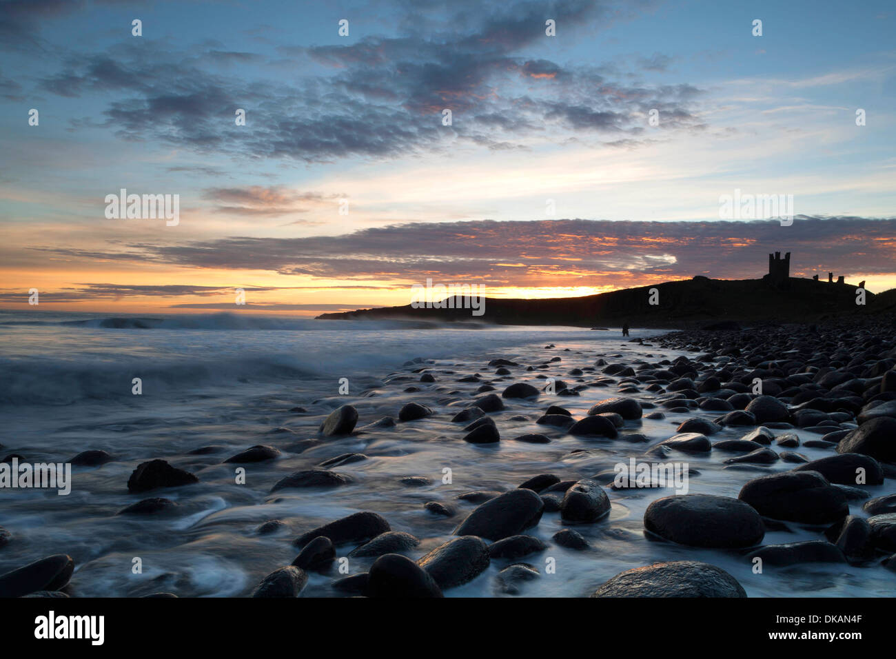 Dunstanburgh Castle, Northumberland, at dawn, viewed from Embleton Bay Stock Photo