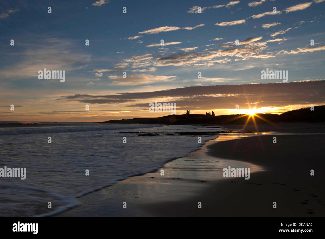 Dunstanburgh Castle, Northumberland, at dawn, viewed from Embleton Bay Stock Photo
