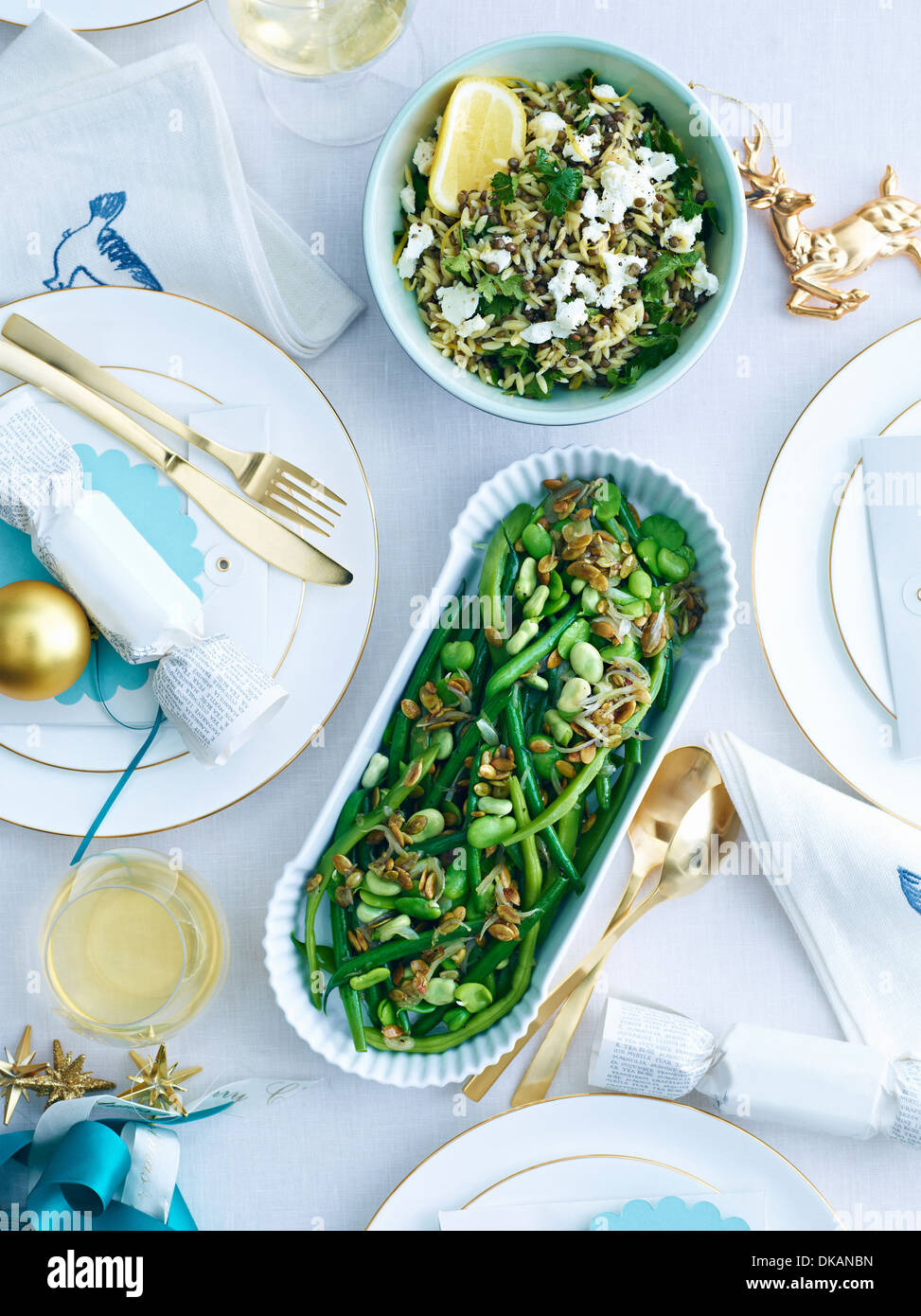 Dishes of lemon orzo and green beans on decorated table Stock Photo