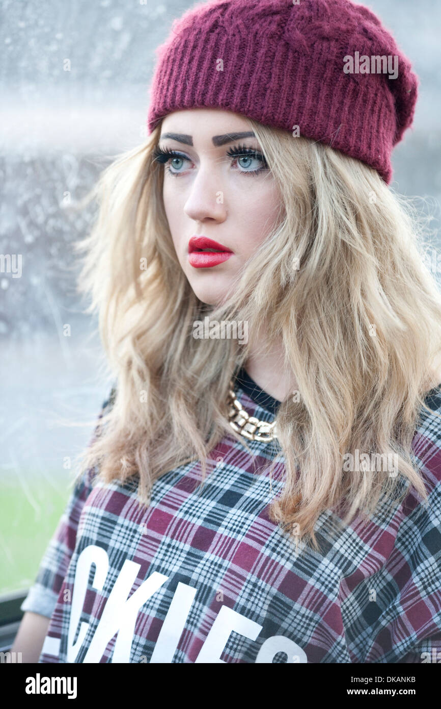 Teenage girl with long blonde hair standing outside at a bus stop. Stock Photo