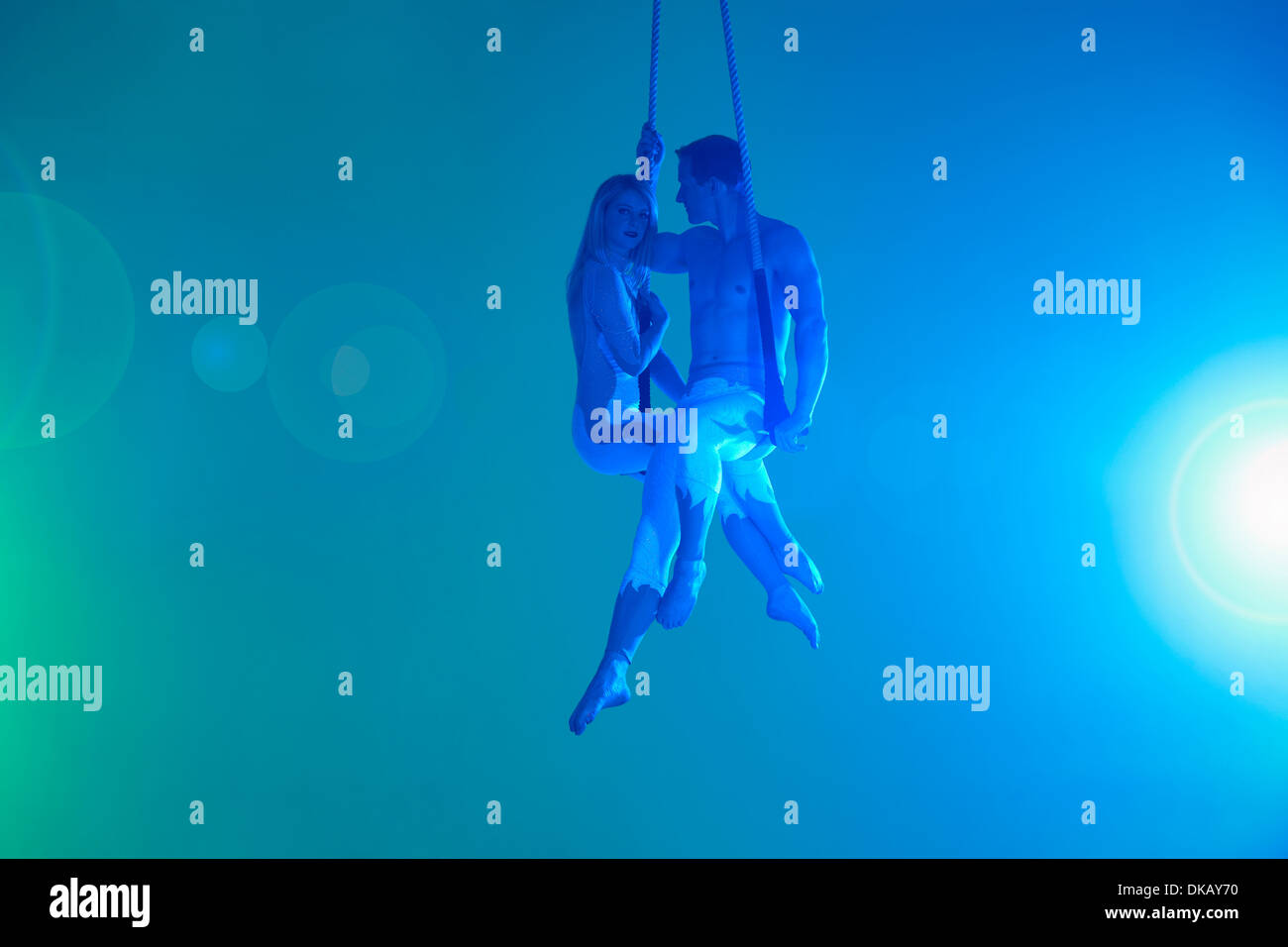 Couple sitting on trapeze Stock Photo